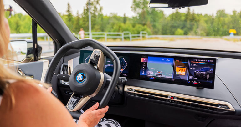 A woman sits in the driver's seat of a modern BMW car that provides connected vehicle services