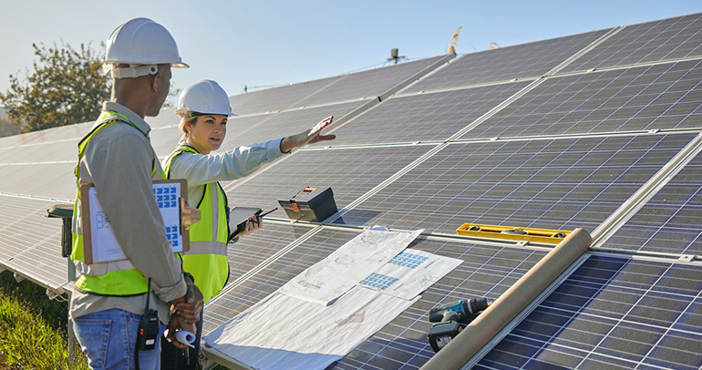 An image of two utility workers out in the field planning solar panel install for customers