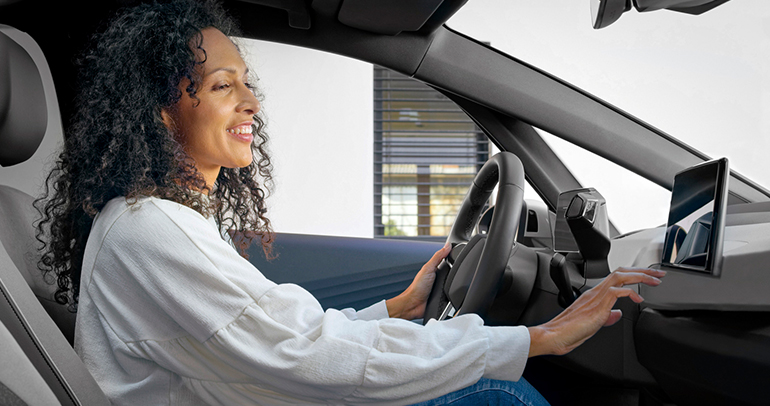 A woman using the connected vehicle services in her car before driving off