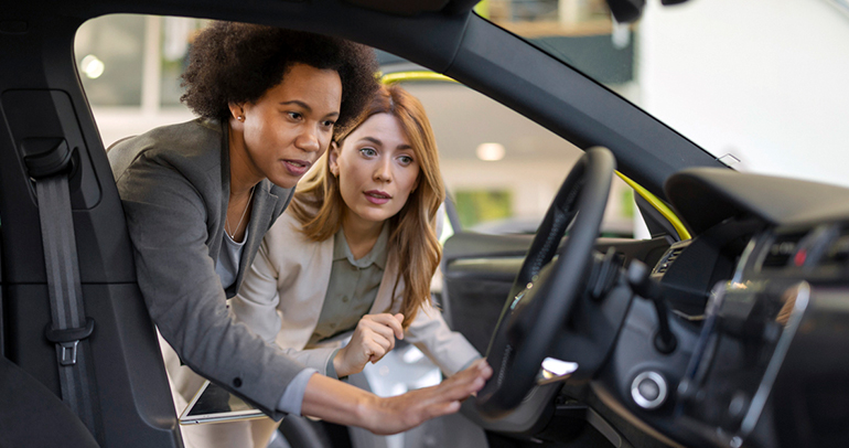 Two women deciding if the battery electric vehicle (BEV) at the dealership is the right purchase for them