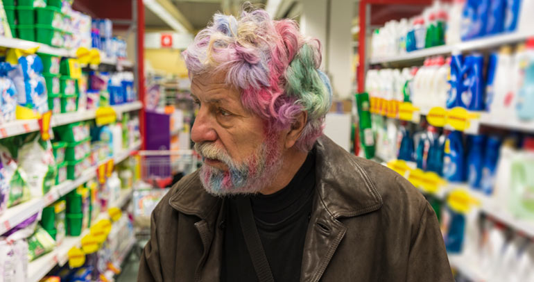 A senior man with rainbow colored hair grocery shopping