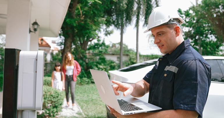 A utility technician reads the energy meter while making a service call to a customer's home