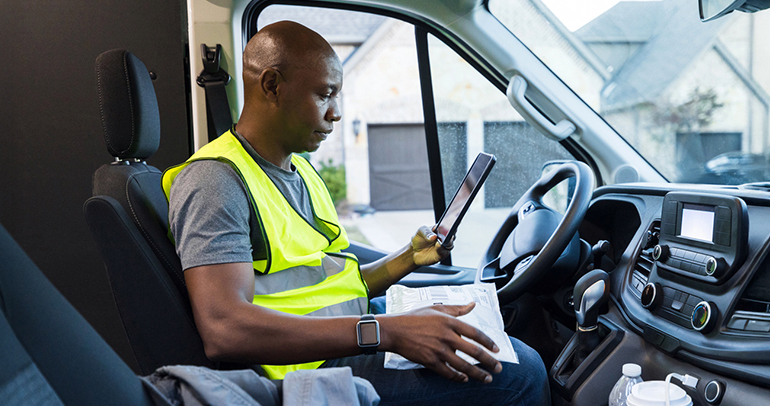 A delivery driver using a tablet while in his delivery truck
