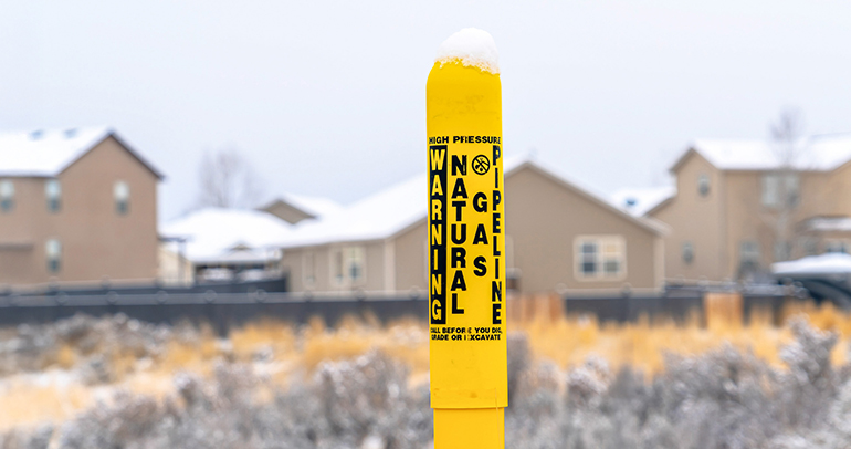Pole marker with warning sign for natural gas pipelines buried underground