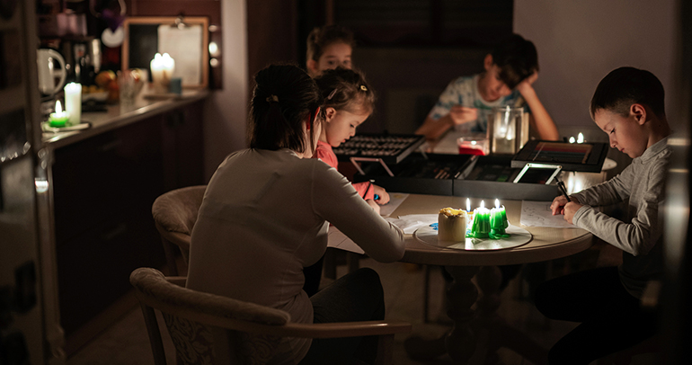 A family around a table with candles lit during an energy power outage