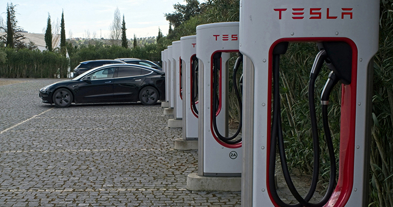 A solid black Tesla Model 3 dual motor charging at the Supercharger