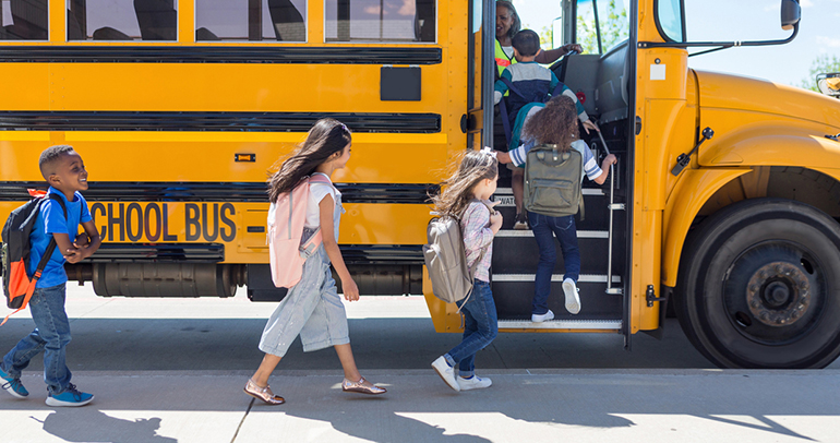 A group of school children getting on a school bus