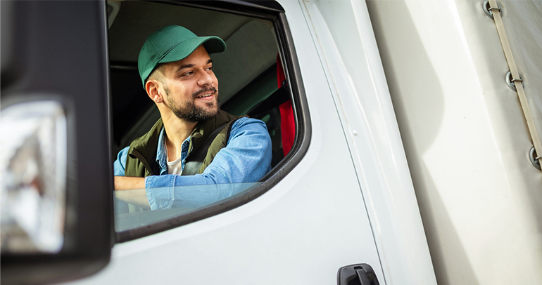 A commercial vehicle driver looking out the window of his truck as he backs up