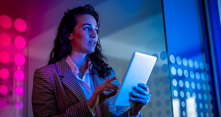 A women holding a tablet in one hand.