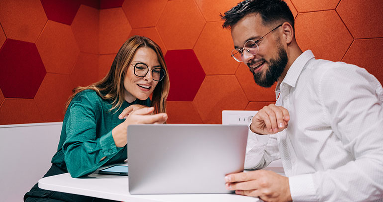 Two colleagues looking at a laptop screen
