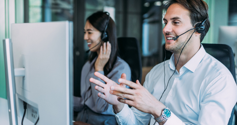 Two customer service representatives in an office talking to utility customers on the phone